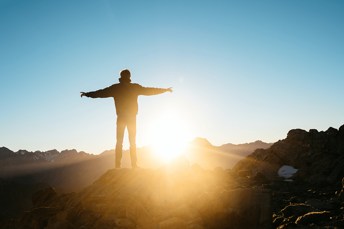 man with arms stretched out on mountaintop