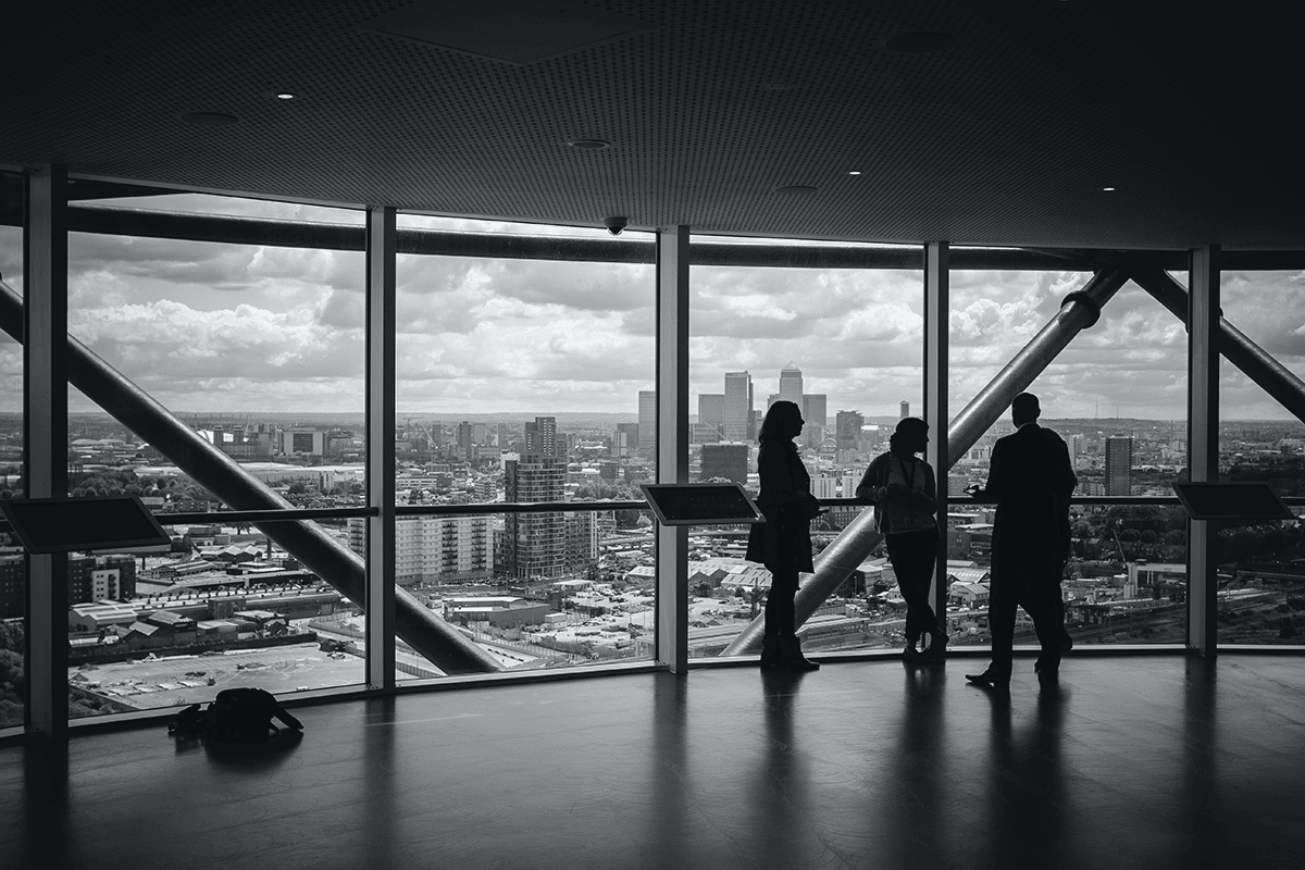 people standing in silhouette in large skyscraper