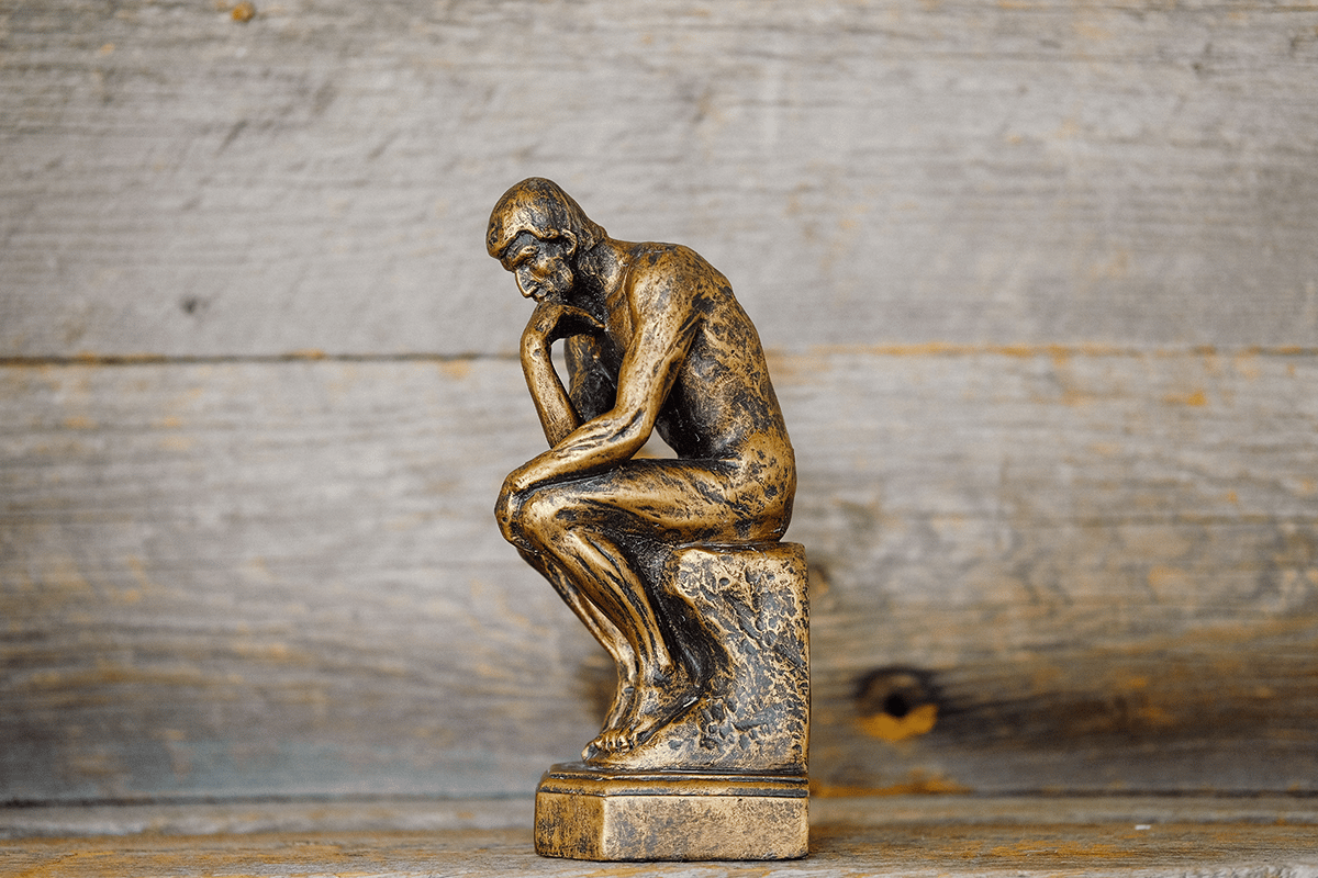 small thinking man statue on wooden shelf