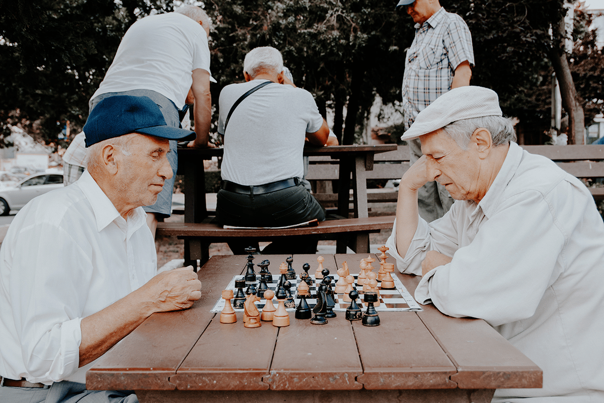 two older men playing chess outside