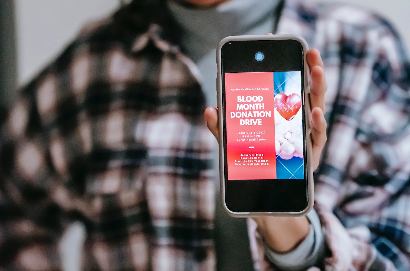 person holding mobile phone with blood month donation message