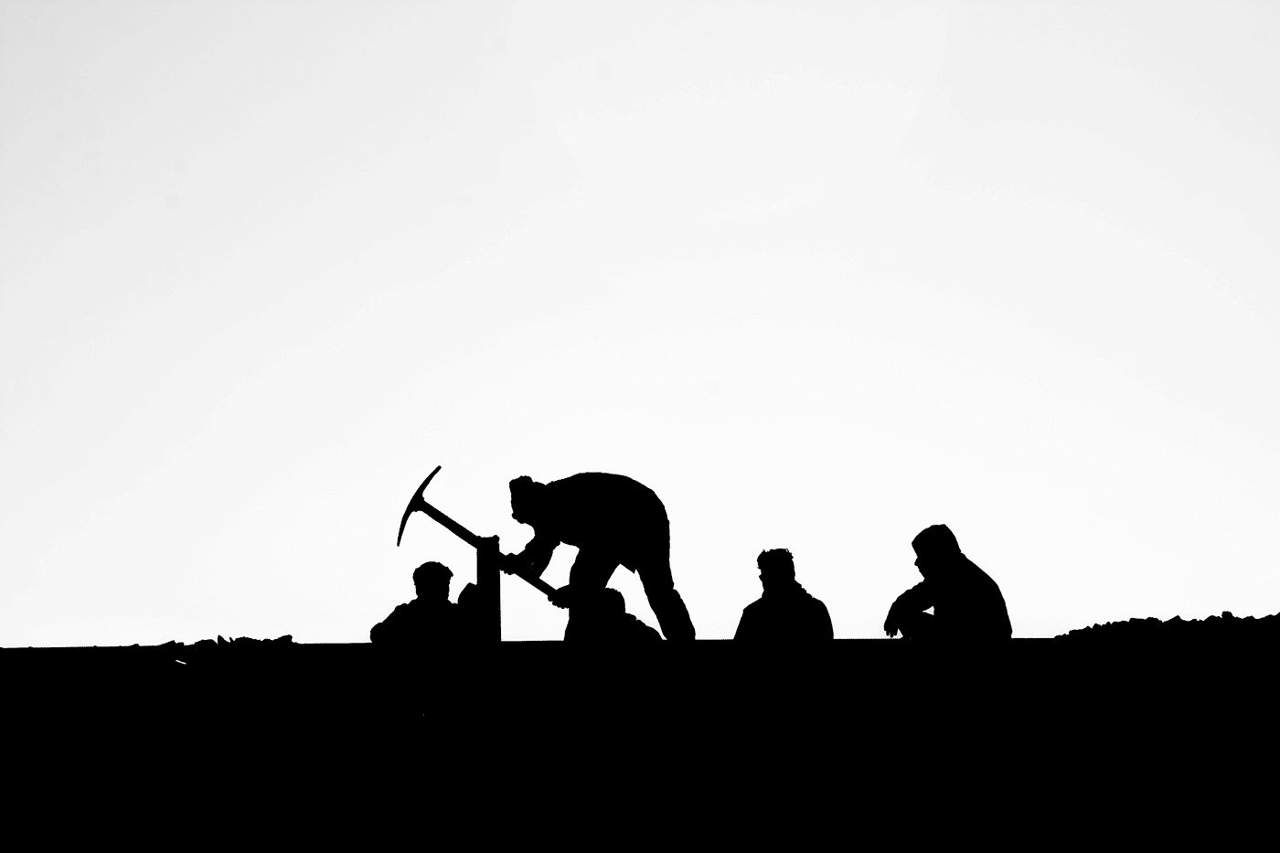 silhouette of people working in a field with a pickaxe