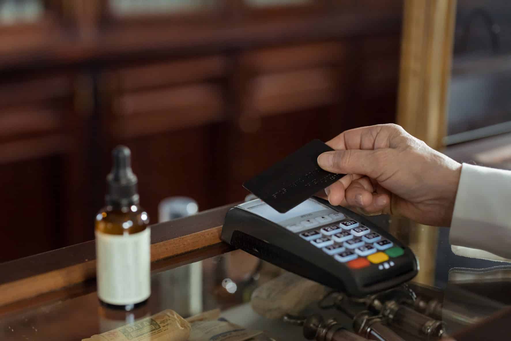 hand holding a credit card over a credit card machine