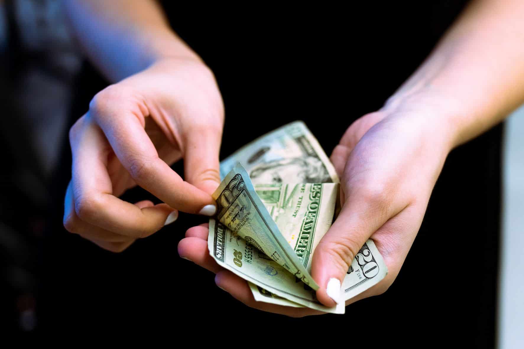 person counting money in open hand