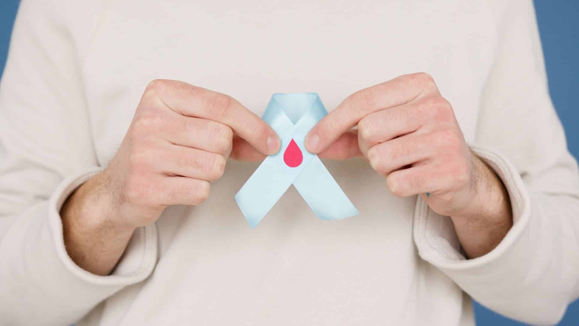 person holding a light blue ribbon with a blood drop icon