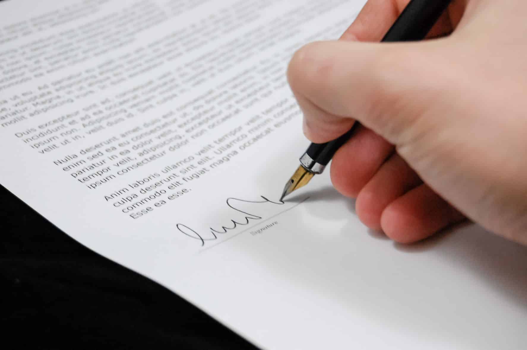 person signing a paper with latin text