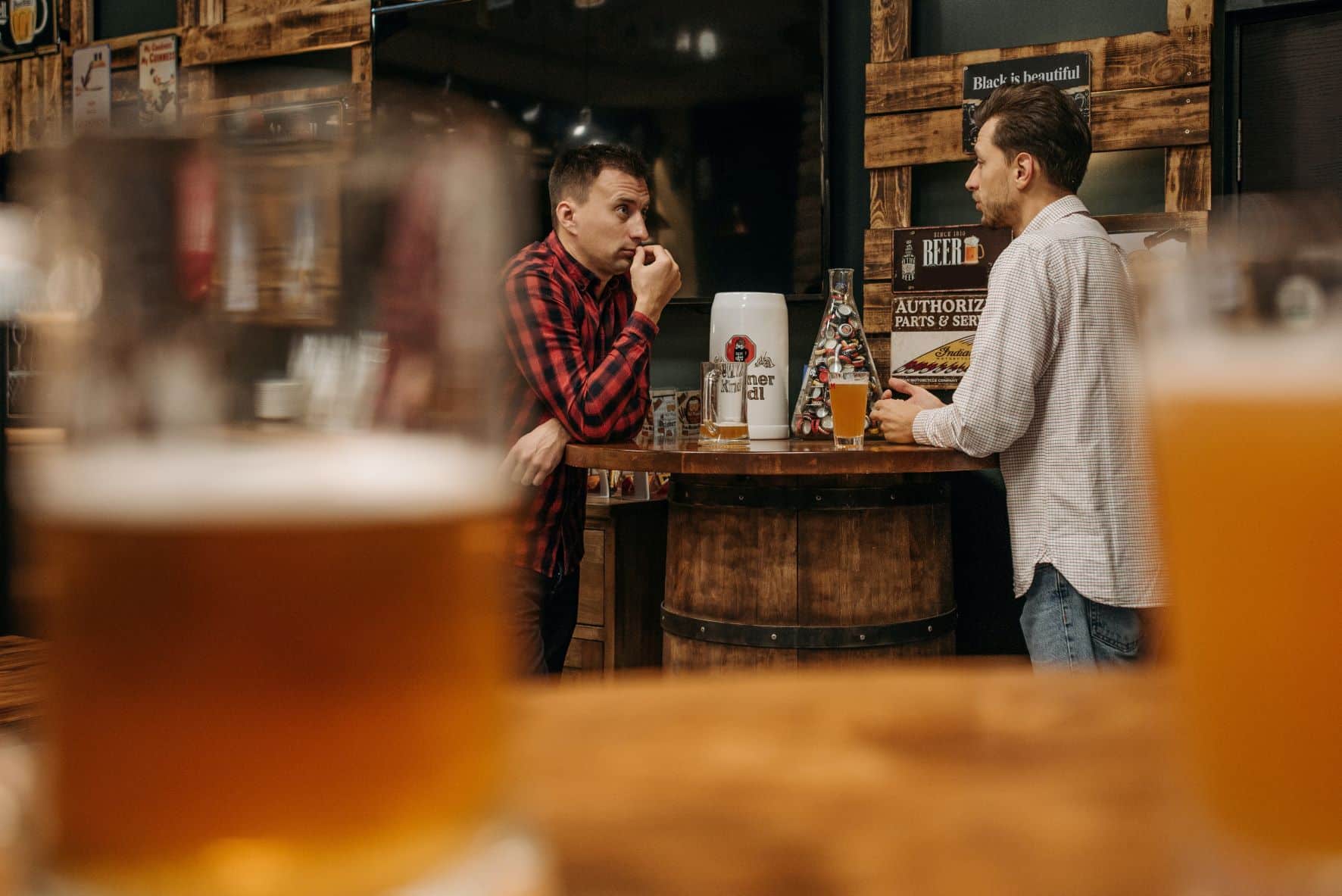 two men speaking across a table in a bar