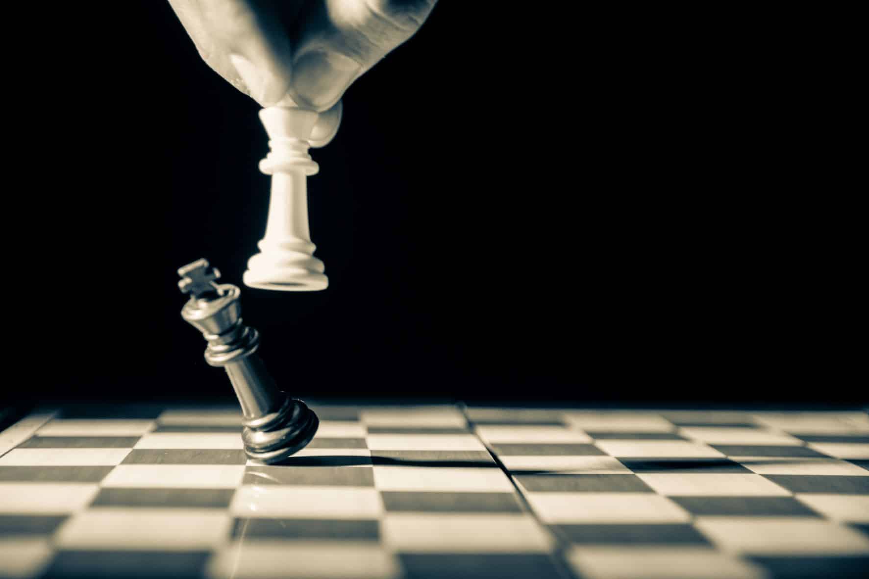 white pawn knocking over a black pawn on chessboard