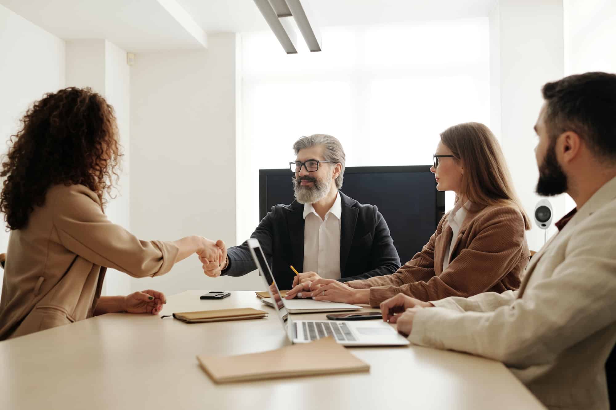 group of people sitting around office table shaking hands