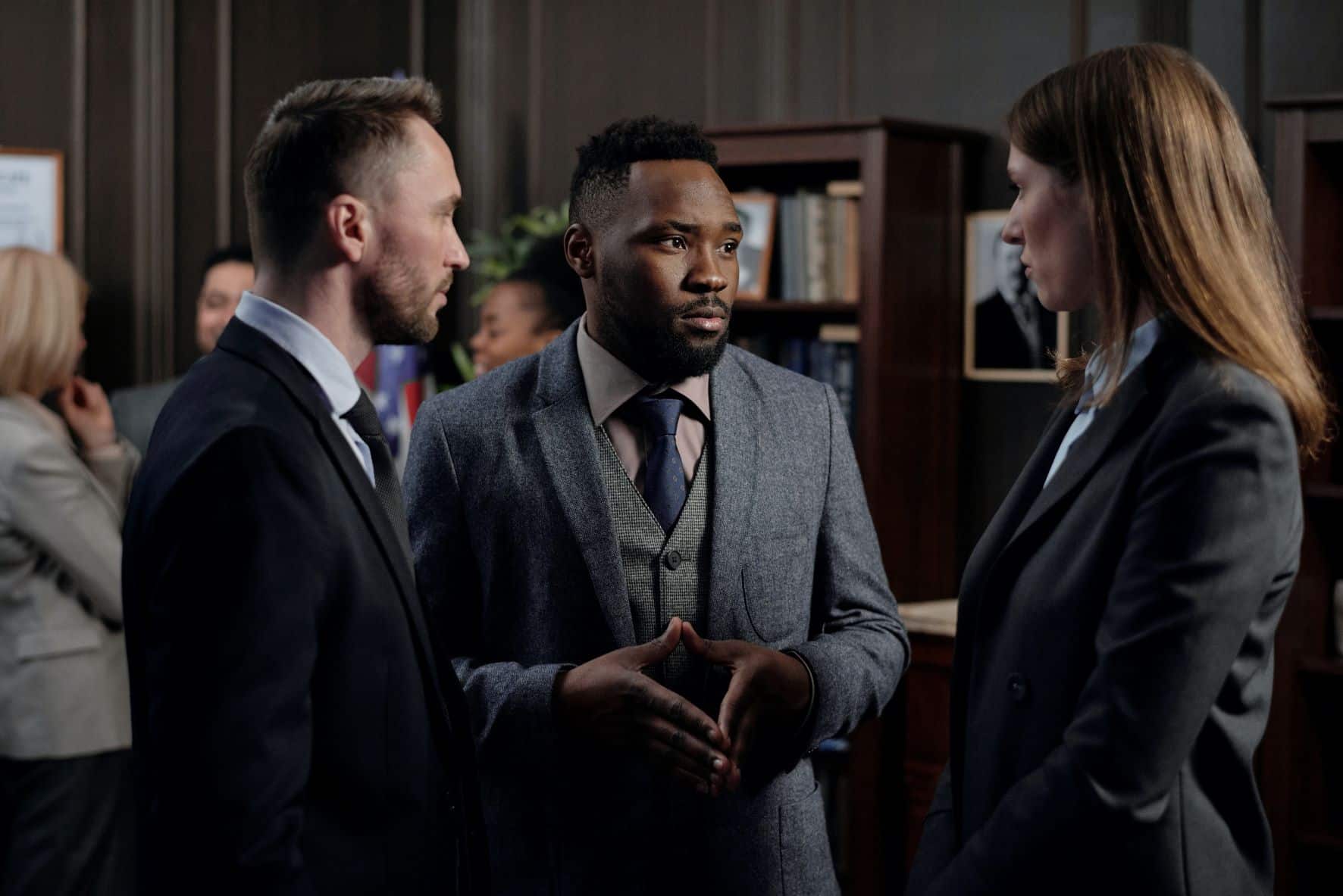 group of three people in suits having a conversation