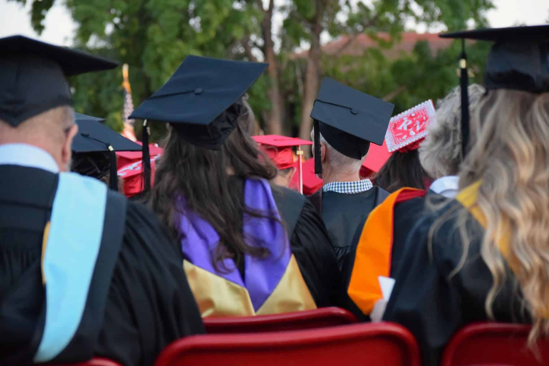 people sitting at graduation ceremony wearing traditional hats