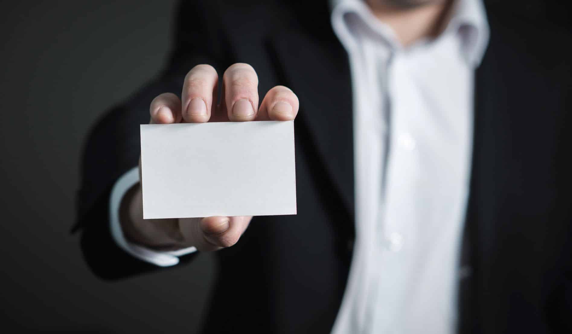 person in suit holding out a blank set of business cards