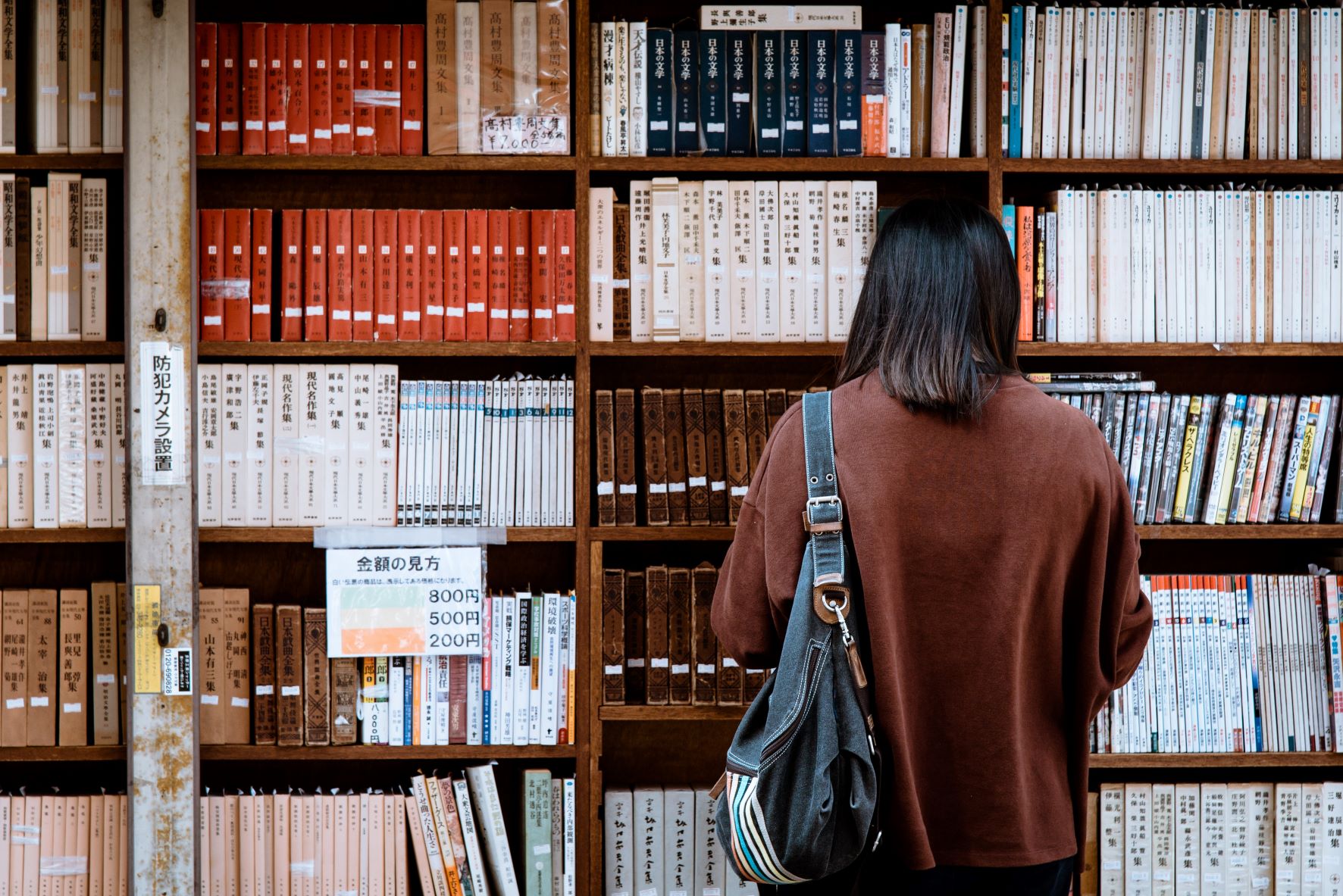 person standing in front of university bookshelf
