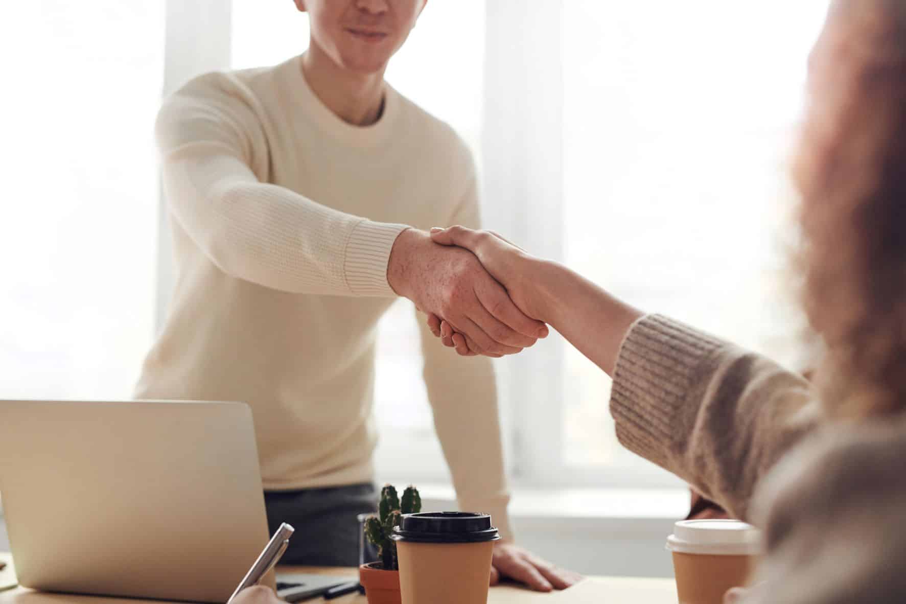 two people shaking hands over an office desk